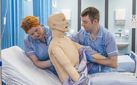 Two nurses supporting a mannequin